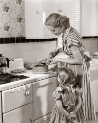 1950s-housewife-in-kitchen-decorating-cake-on-stove-with-pastry-gun-CTG1E2.jpg